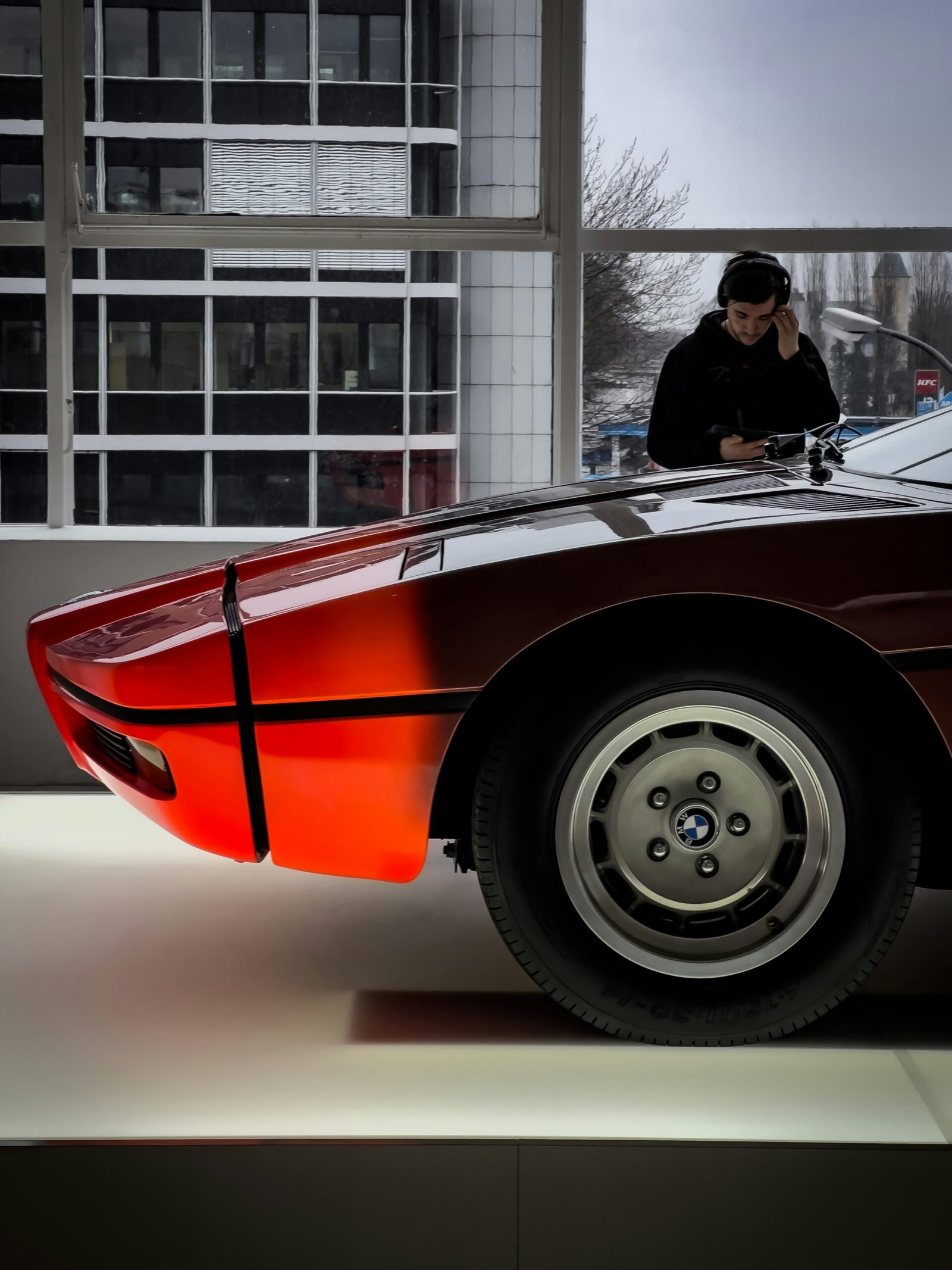 a man sitting on top of a red sports car